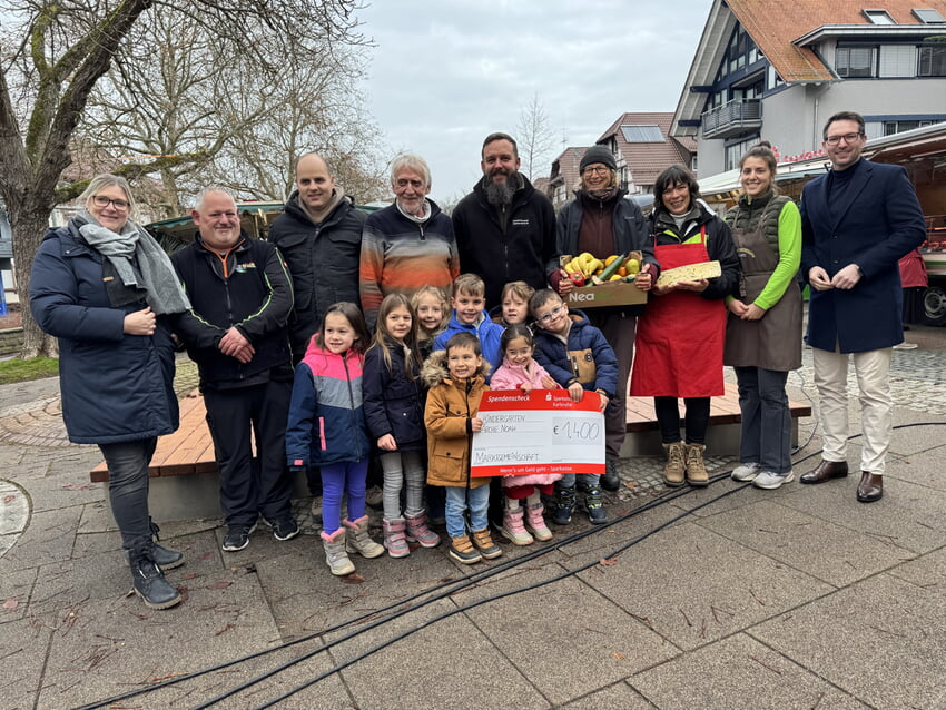 Die Händlerinnen und Händler des Langensteinbacher Wochenmarktes zusammen mit Kindergartenleiterin Katharina Becker, sowie Bürgermeister Björn Kornmüller und glücklichen Kindern des „Arche Noah“-Kindergartens bei der Übergabe des Spendenchecks Foto: Gemeinde Karlsbad