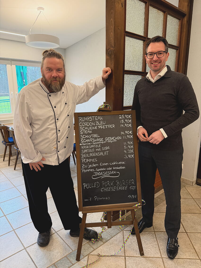 Kulinarischer Austausch beim Antrittsbesuch: Koch und Betreiber Stefan Hanuschka pr&auml;sentiert B&uuml;rgermeister Bj&ouml;rn Kornm&uuml;ller das durchdachte Konzept und die kleine, aber feine Speisekarte des Lokals. Foto: Gemeinde Karlsbad