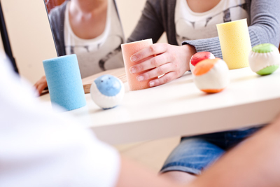 Eine Hand greift verschiedene Bälle und Zylinder